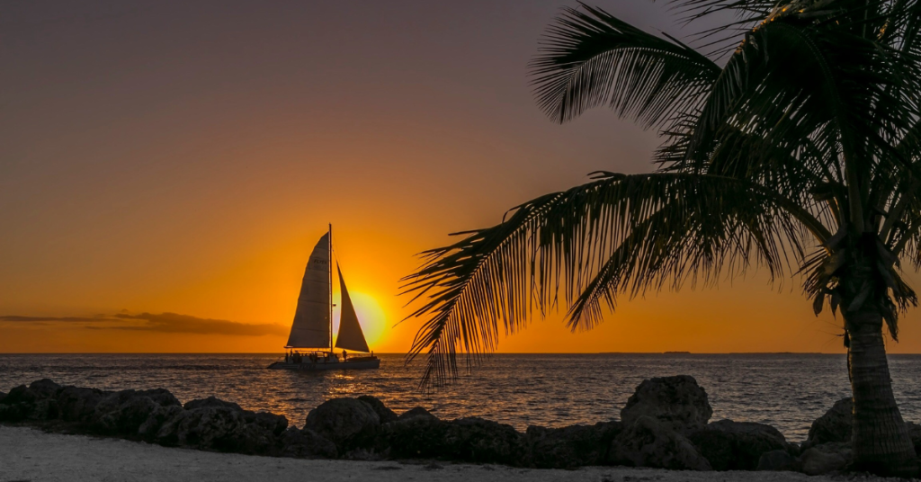 "Group of young adults enjoying a vibrant sunset at key west island, one of the best places in Florida for young adults to vacation, showing a lively boardwalk scene with palm trees and beach activities."