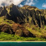 Scenic view of a tropical Hawaiian beach with turquoise waters, golden sand, lush palm trees, and majestic mountains in the background, capturing the essence of 'The Ultimate Hawaii Travel Guide'.